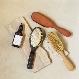 A close up of the vegan hairbrush with tampico fibres and beach wood with a box. 