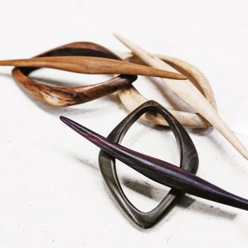 The black orchid hair slide in teak, tamarind and rosewood close up view on a table