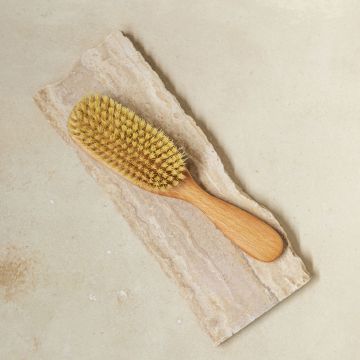 A close up of the vegan hairbrush with tampico fibres and beach wood with a box. 